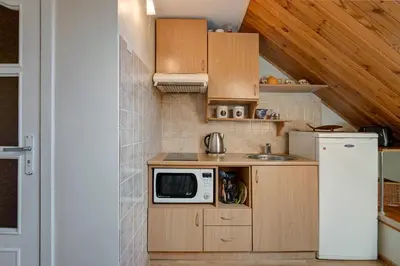 a small kitchen with wooden cabinets and a microwave at Vidos Apartamentai in Vilnius
