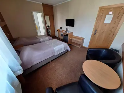 a hotel room with a bed and a table and chairs at Home B&B in Kaunas