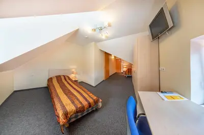 a bedroom with a bed and a desk and a tv at Hotel - Bar Grafaite in Šiauliai