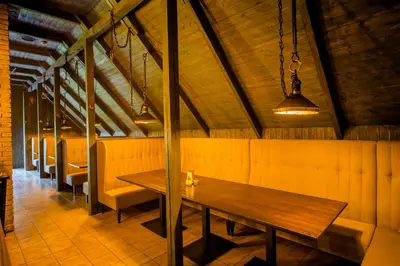 a dining room with a wooden table and benches at Hotel - Bar Grafaite in Šiauliai