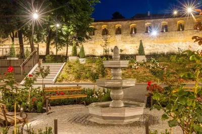 a fountain in a garden with benches and a building at Domus Maria in Vilnius