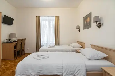 a hotel room with two beds and a desk at Domus Maria in Vilnius