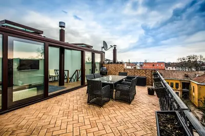 a patio with a table and chairs on a roof at Apartment with a Terrace over the Old Town Two Bedrooms in Kaunas