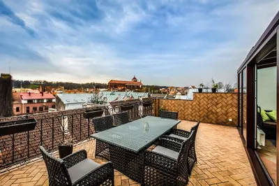 a patio with a table and chairs on a balcony at Apartment with a Terrace over the Old Town Two Bedrooms in Kaunas