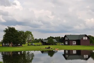 a house next to a body of water at Sodyba Puodžių Kaimas in Mackėnai