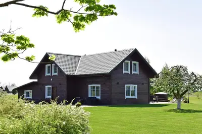 a house with a black roof on a green lawn at Sodyba Puodžių Kaimas in Mackėnai