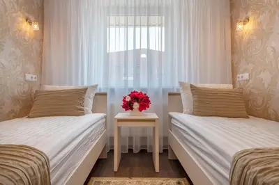 a bedroom with two beds and a vase of flowers on a table at Kesminta Šalčininkai in Šalčininkai