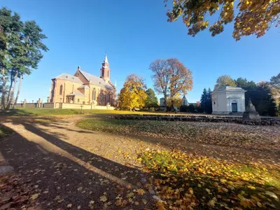 an old house with a church in the background at Aido ir Jovitos sodyba Jorunas in Kernavė