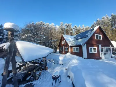 a house covered in snow in front of a cabin at Aido ir Jovitos sodyba Jorunas in Kernavė