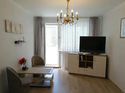 a living room with a flat screen tv and a table at Šiauliai City Apartment in Šiauliai