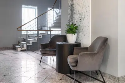 two chairs and a table in a room with stairs at Domus Hotel in Birštonas