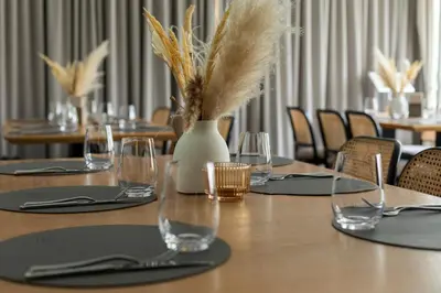 a table with wine glasses and a vase with feathers at Domus Hotel in Birštonas