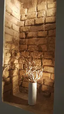 a white vase with branches in front of a brick wall at Apartment on Kudirkos 20 in Vilnius