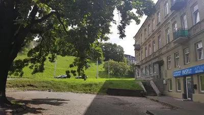 a building on a street next to a grass field at Apartment on Kudirkos 20 in Vilnius