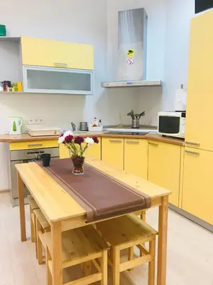a kitchen with yellow cabinets and a wooden table with flowers at Laisves Avenue Hostel 