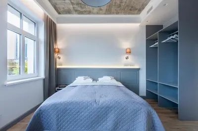 a bedroom with a bed with blue walls and a window at 9010 Apartments in Vilnius