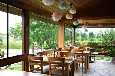 a restaurant with wooden tables and chairs and windows at Mamos virtuve in Avižieniai