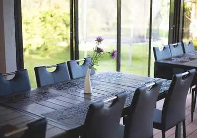 a table with a vase with purple flowers on it at Mamos virtuve in Avižieniai