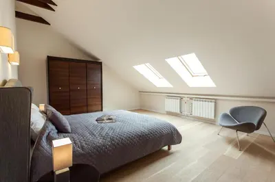 a bedroom with a bed and a chair and skylight at #stayhere - Spacious 2BDR Two Floor I Heart of Old Town in Vilnius