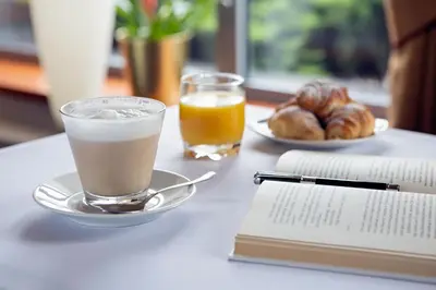 a table topped with a cup of coffee and a book at Art City Inn in Vilnius