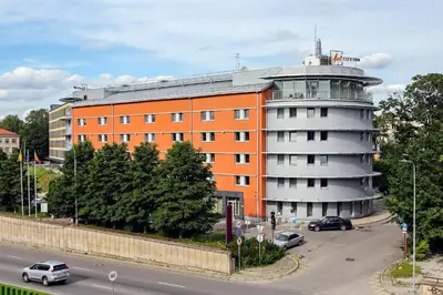 an orange building with a round tower next to a street at Art City Inn in Vilnius