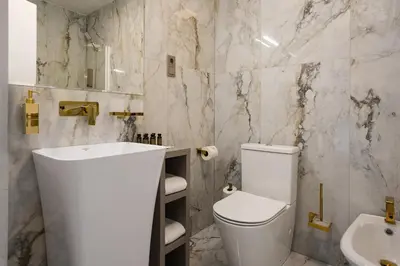 a white bathroom with a toilet and a sink at St Palace Hotel in Vilnius