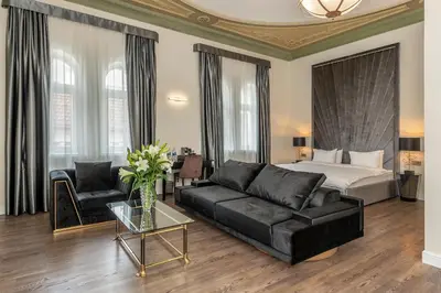 a living room with a bed and a black couch at St Palace Hotel in Vilnius