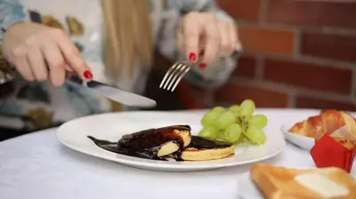 a person eating a plate of food with a fork and knife at BEST WESTERN Santakos Hotel in Kaunas