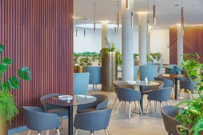a restaurant with tables and chairs and plants at Vilnius Grand Resort in Ežeraičiai