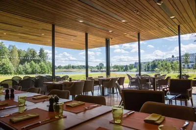 a restaurant with tables and chairs and large windows at Vilnius Grand Resort in Ežeraičiai