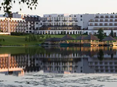 a building with a reflection in the water at Vilnius Grand Resort in Ežeraičiai