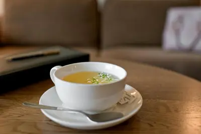 a cup of soup on a table with a spoon at Best Western Vilnius in Vilnius