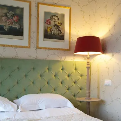 a bedroom with a bed with a green headboard and a lamp at Hotel Apia in Vilnius
