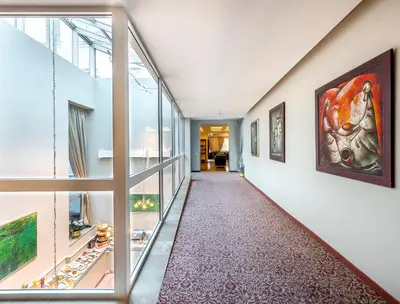 an empty hallway with glass doors and paintings on the walls at Ratonda Centrum Hotels in Vilnius