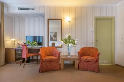 a room with two chairs and a table and a television at Artis Centrum Hotels in Vilnius