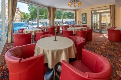 a restaurant with red chairs and tables and windows at Artis Centrum Hotels in Vilnius