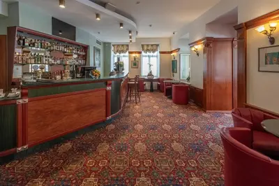 a bar in a hotel with red chairs at Artis Centrum Hotels in Vilnius
