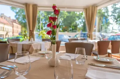 a table with glasses and a vase with flowers on it at Artis Centrum Hotels in Vilnius