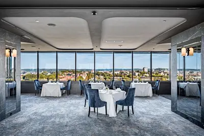 a restaurant with tables and chairs and large windows at VILNIUS PARK PLAZA HOTEL & SPA, Restaurant, Panorama Bar, Conference & Banquet Center in Vilnius