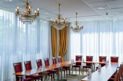 a conference room with long tables and chairs and chandeliers at VILNIUS PARK PLAZA HOTEL & SPA, Restaurant, Panorama Bar, Conference & Banquet Center in Vilnius