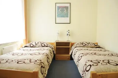 a bedroom with two beds and a table and a picture at Amicus Hotel in Vilnius