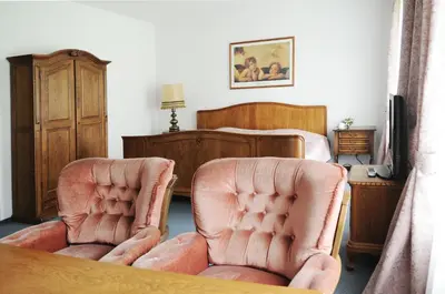 a bedroom with two pink chairs and a bed at Amicus Hotel in Vilnius