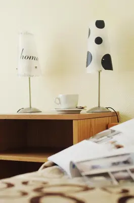 a table with a lamp and a cup on a bed at Amicus Hotel in Vilnius