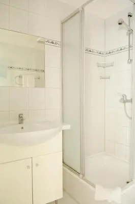 a white bathroom with a shower and a sink at Amicus Hotel in Vilnius