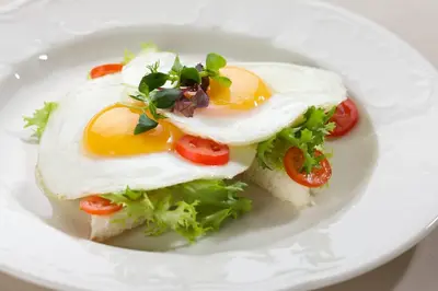 a white plate with a sandwich with eggs and lettuce at Imperial Hotel & Restaurant in Vilnius