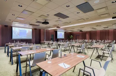 a conference room with tables and chairs and a projection screen at Radisson Blu Hotel Lietuva in Vilnius