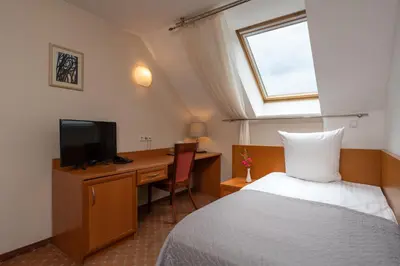 a bedroom with a bed and a desk with a television at Mabre Residence in Vilnius