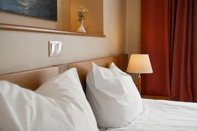 a bedroom with a bed with white pillows and a lamp at Mabre Residence in Vilnius