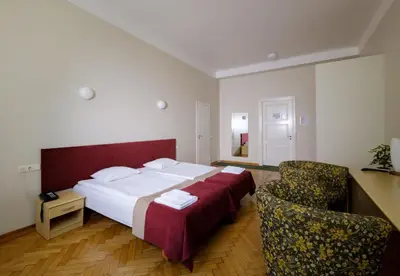 a bedroom with a large bed and two chairs at Hotel Metropolis in Kaunas