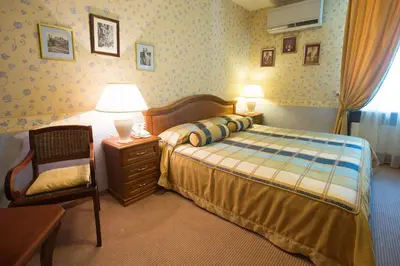 a bedroom with a bed and a chair and lamps at Shakespeare Boutique Hotel in Vilnius